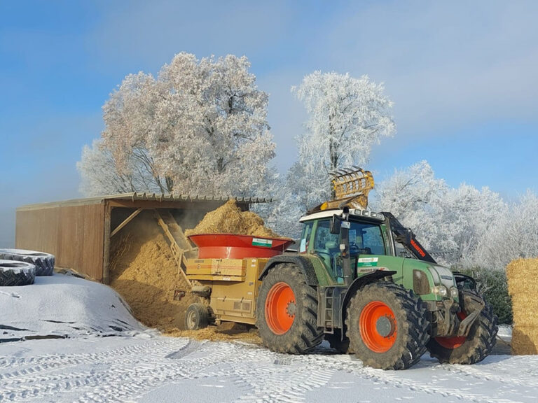 Auf dem Bild sieht man einen Traktor mit der Strohmühle im Einsatz.